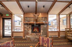 Interior space with a fireplace, dark colored carpet, beamed ceiling, and a baseboard radiator