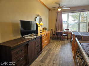 Living room with light wood-type flooring, a textured ceiling, ornamental molding, and ceiling fan