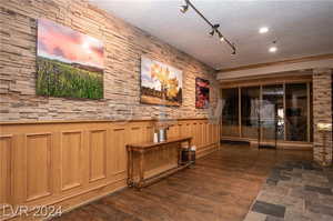 Hallway featuring track lighting, a textured ceiling, and dark wood-type flooring