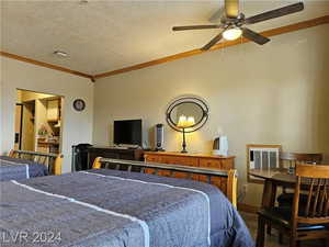 Bedroom with ceiling fan, a textured ceiling, crown molding, and hardwood / wood-style floors