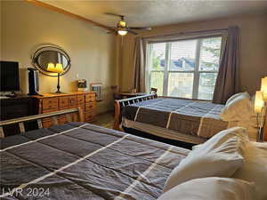 Bedroom with ceiling fan, a textured ceiling, and dark hardwood / wood-style flooring