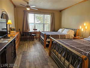 Bedroom featuring a textured ceiling, ceiling fan, dark wood-type flooring, and crown molding