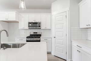 Kitchen with white cabinetry, sink, and appliances with stainless steel finishes