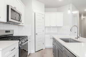 Kitchen featuring stainless steel appliances, sink, and white cabinets