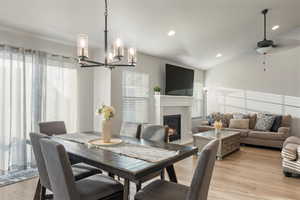 Dining area featuring light hardwood / wood-style floors, ceiling fan with notable chandelier, and lofted ceiling