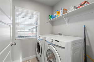 Washroom with washing machine and clothes dryer and light tile patterned floors