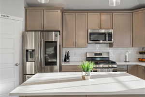 Kitchen with stainless steel appliances and decorative backsplash