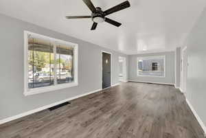 Unfurnished living room featuring ceiling fan and dark hardwood / wood-style flooring