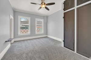 Empty room with carpet flooring, ornamental molding, and ceiling fan