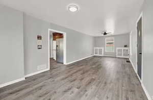 Unfurnished living room with dark hardwood / wood-style flooring and ceiling fan