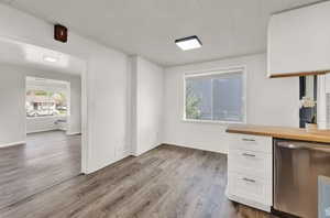 Kitchen with white cabinets, dishwasher, dark wood-type flooring, and butcher block counters