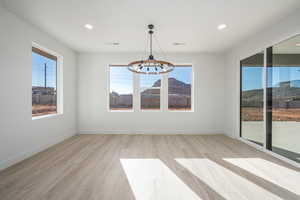 Unfurnished dining area featuring a wealth of natural light, a chandelier, and light hardwood / wood-style floors