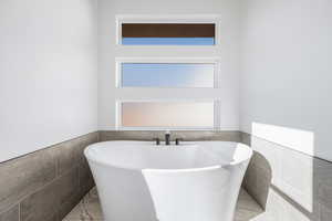 Bathroom featuring a tub to relax in and tile walls