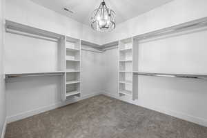 Walk in closet featuring carpet floors and an inviting chandelier