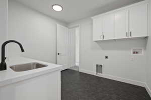 Laundry area featuring washer hookup, hookup for an electric dryer, dark tile patterned floors, cabinets, and sink