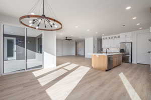 Kitchen with a kitchen island with sink, sink, white cabinets, light hardwood / wood-style flooring, and stainless steel appliances