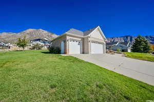 View of side of home featuring a mountain view, a garage, and a yard