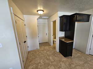 Kitchen featuring a textured ceiling, light stone countertops, and light tile patterned floors