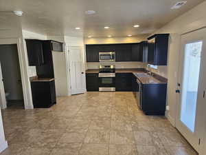 Kitchen featuring stainless steel appliances, dark stone countertops, a textured ceiling, and sink