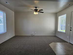 Carpeted empty room with ceiling fan, plenty of natural light, and a textured ceiling