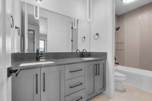 Full bathroom featuring vanity, tiled shower / bath combo, toilet, and tile patterned floors