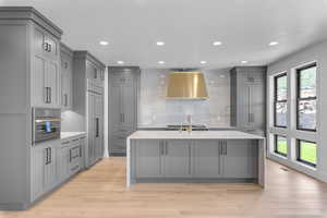 Kitchen featuring backsplash, wall chimney range hood, gray cabinets, appliances with stainless steel finishes, and light wood-type flooring