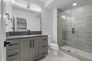 Bathroom with a shower with shower door, vanity, a textured ceiling, toilet, and tile patterned floors