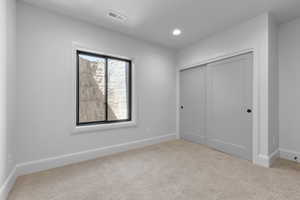 Unfurnished bedroom featuring light carpet and a closet