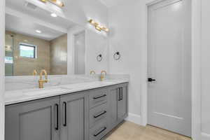 Bathroom with vanity, tile patterned flooring, and tiled shower