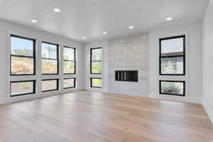 Unfurnished living room featuring light wood-type flooring and a tiled fireplace