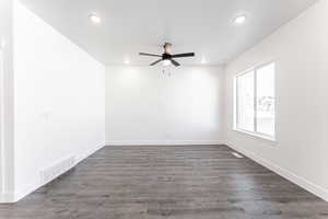 Empty room featuring dark hardwood / wood-style flooring and ceiling fan