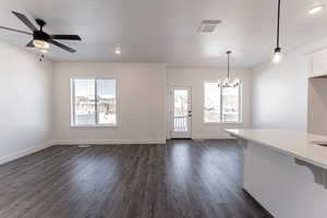 Interior space with ceiling fan with notable chandelier, dark hardwood / wood-style floors, a textured ceiling, and a wealth of natural light