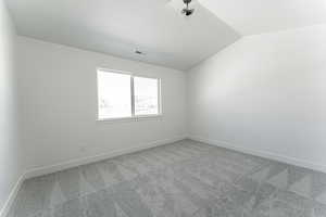 Carpeted empty room featuring lofted ceiling and a textured ceiling