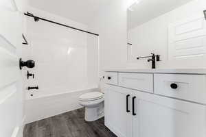 Full bathroom featuring hardwood / wood-style flooring, vanity, toilet, and washtub / shower combination