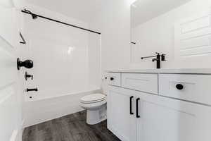 Full bathroom featuring bathtub / shower combination, toilet, vanity, and wood-type flooring