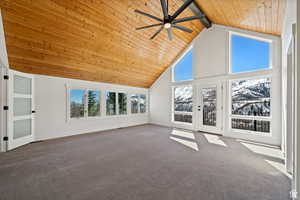 Unfurnished living room with high vaulted ceiling, ceiling fan, beamed ceiling, and carpet flooring