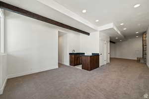 Unfurnished living room with light carpet and beam ceiling