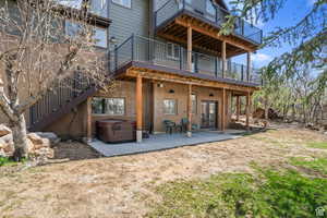 Back of property with a hot tub, a patio area, and a deck