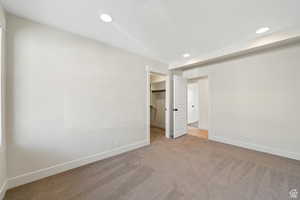 Unfurnished bedroom with light carpet, a walk in closet, and a closet