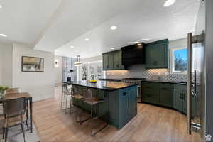 Kitchen with high end stove, a wealth of natural light, custom exhaust hood, and decorative light fixtures