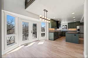 Kitchen featuring hanging light fixtures, french doors, stainless steel appliances, a center island, and light wood-type flooring