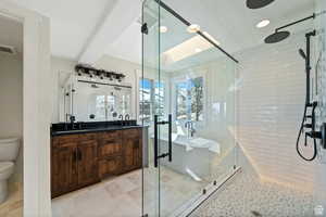 Bathroom featuring a shower with door, toilet, vanity, and tile patterned floors