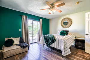 Bedroom featuring a textured ceiling, dark hardwood / wood-style flooring, ceiling fan, and access to exterior