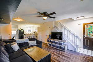 Living room with a textured ceiling, dark hardwood / wood-style floors, and ceiling fan