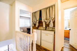 Laundry room with a textured ceiling, dark wood-type flooring, independent washer and dryer, and ceiling fan