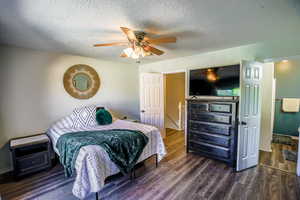 Bedroom with a textured ceiling, dark hardwood / wood-style flooring, and ceiling fan