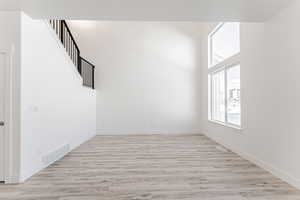 Empty room with a high ceiling and light hardwood / wood-style floors