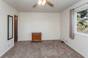 Carpeted spare room featuring ceiling fan