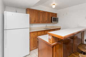 Kitchen with sink, white fridge, and kitchen peninsula