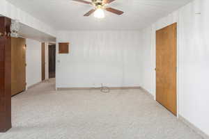 Empty room with ceiling fan and light carpet